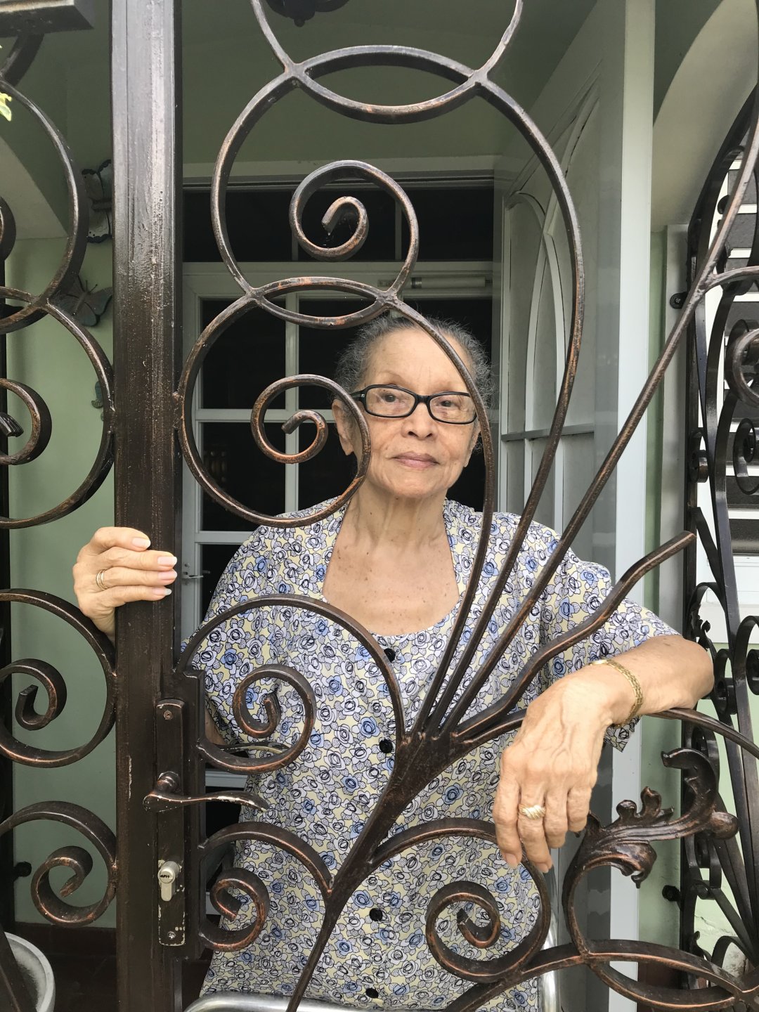 Edra Soto's mother, Luisa V. de Soto, standing inside a metal gate with spirals