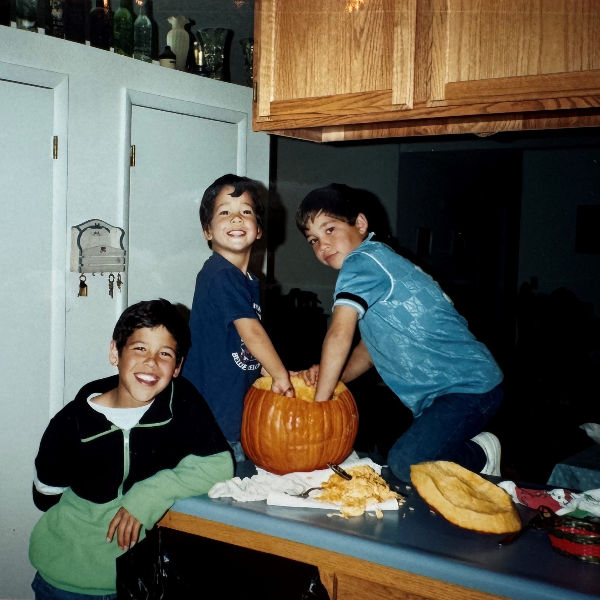 Childhood photo of Joe Dangaran and two brothers carving a pumpkin on the kitchen counter