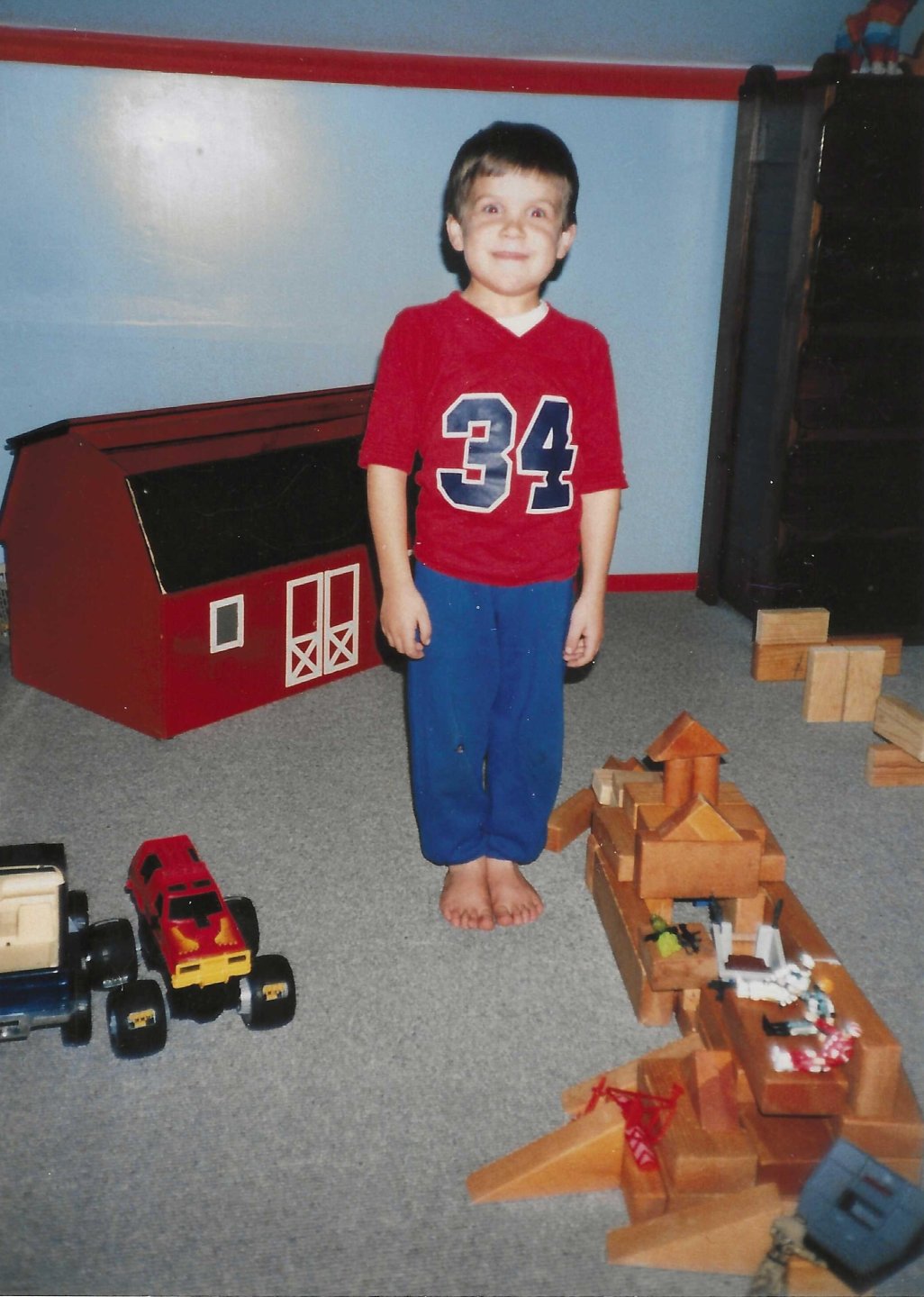 Jonathan Nesci as a child standing with wooden blocks and other toys