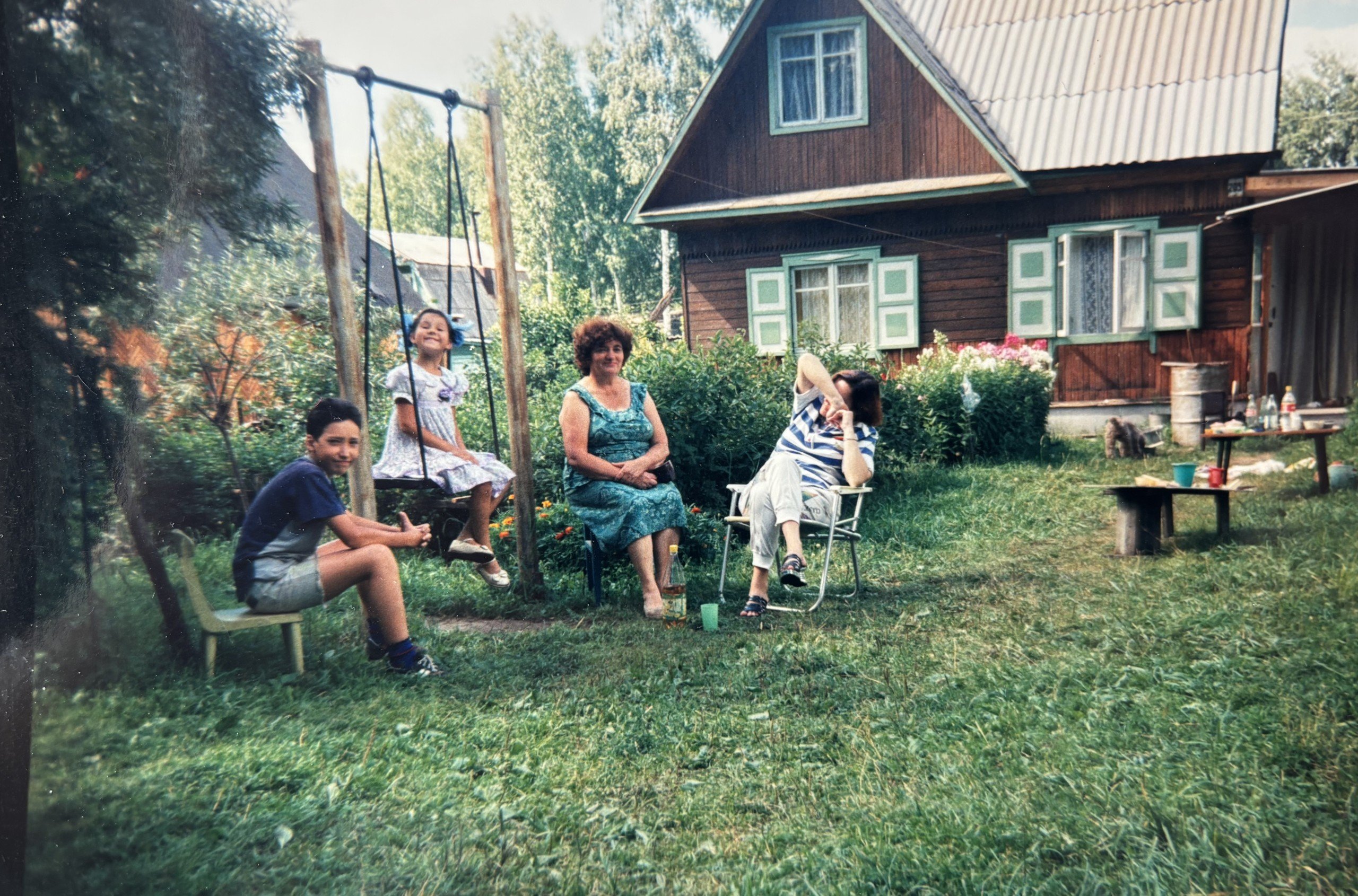 Julia Gamolina and family sitting on an around swing in dacha yard