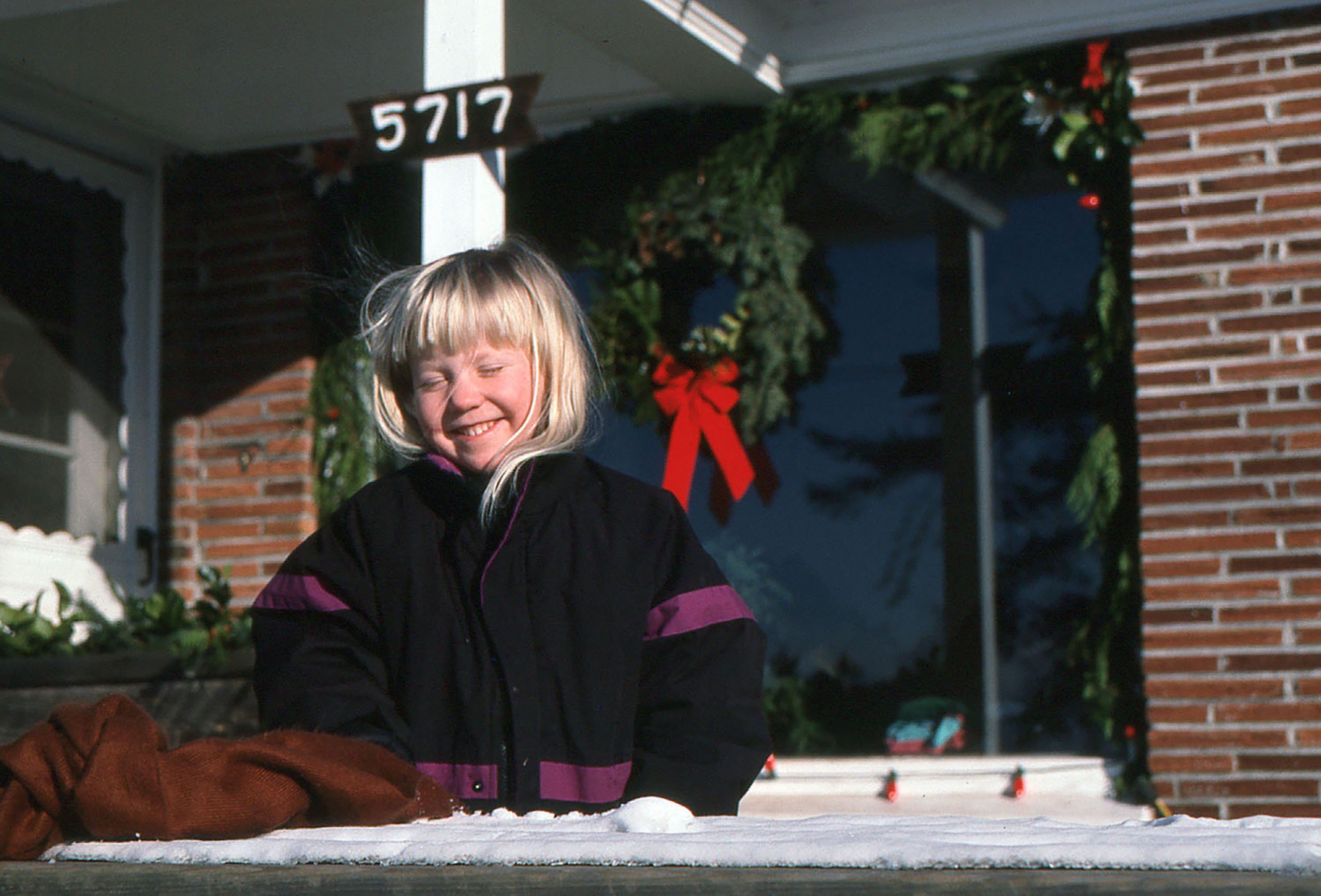 A little girl wearing a black and purple coat