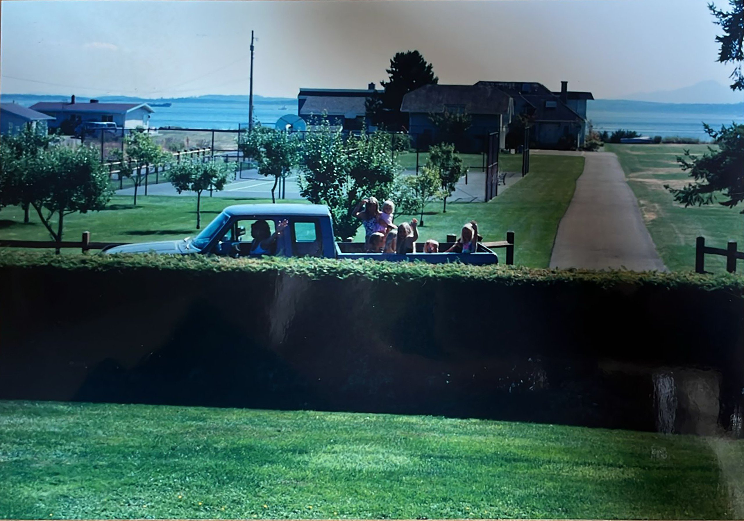 Vintage photo of family and friends waving from truck outside of Whidbey Island, WA, home