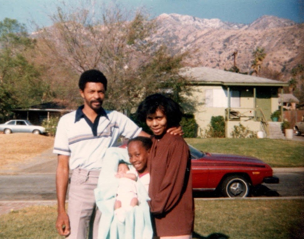 Kenturah Davis as a baby posing with parents and sister in front of her grandmother's house