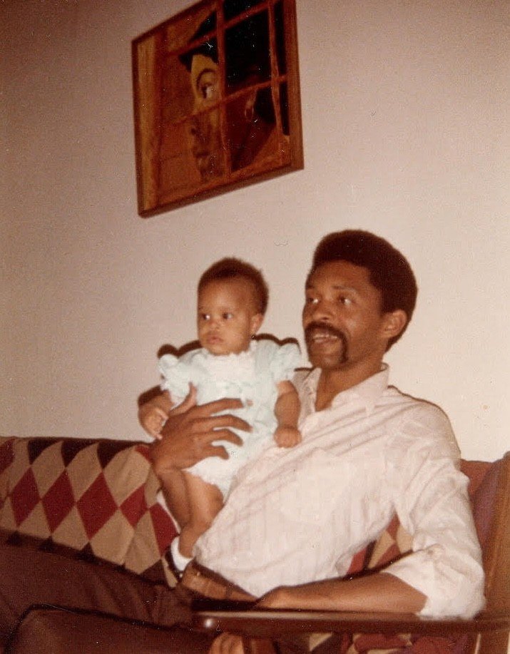 Baby photo of artist Kenturah Davis sitting on the couch with her father
