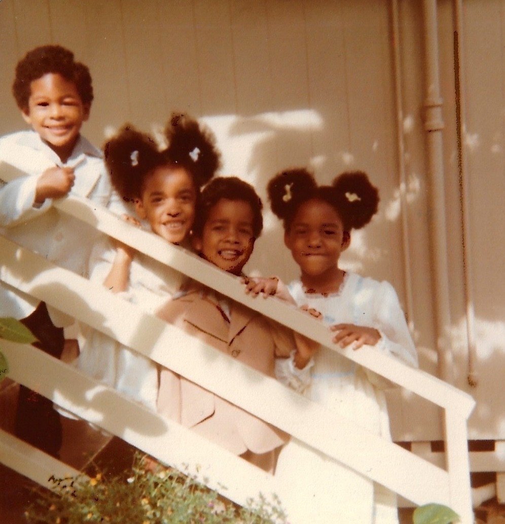 Four children wearing Easter outfits standing on a white staircase outside