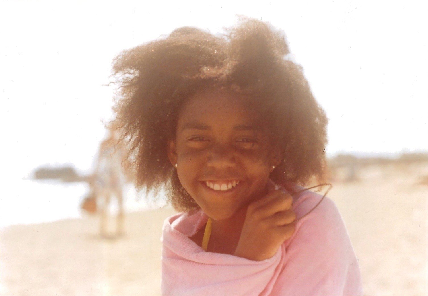Childhood photo of Little Wing Lee smiling on the beach
