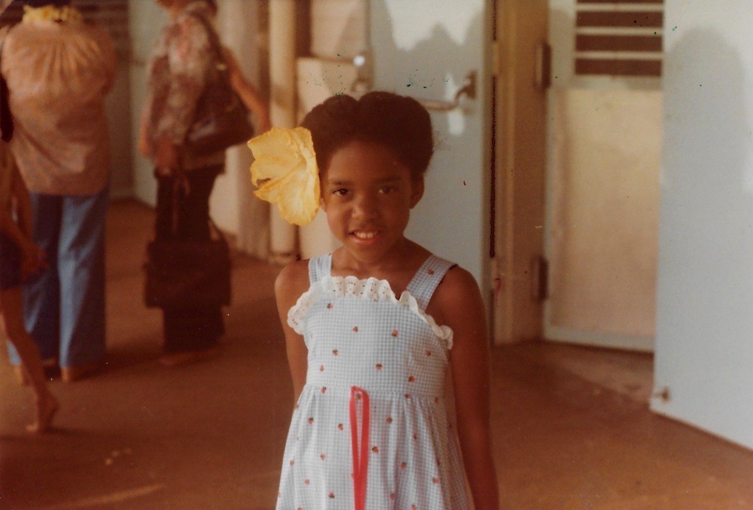 Little girl smiling with a hibiscus flower tucked behind her ear