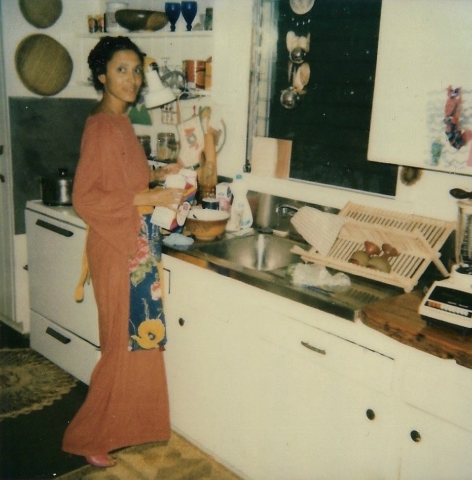 Vintage shot of a young woman standing at a white kitchen with an apron on