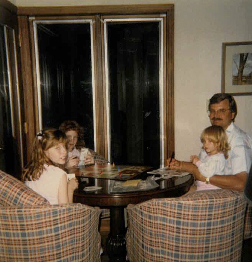 Childhood photo of Sam Klemick's family sitting around a table in plaid leather chairs