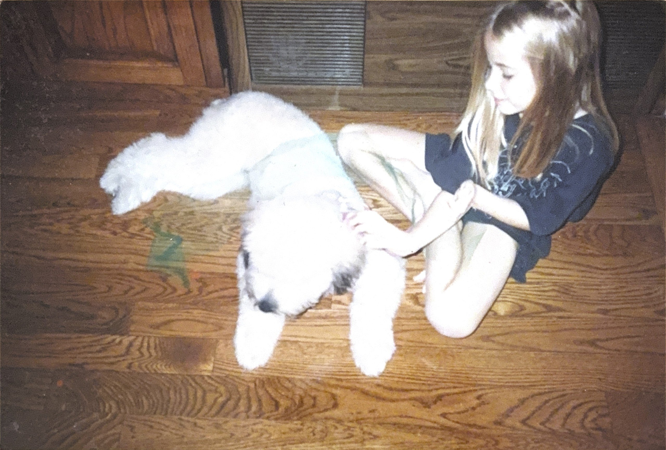 Childhood photo of Sam Klemick sitting on the floor with her dog