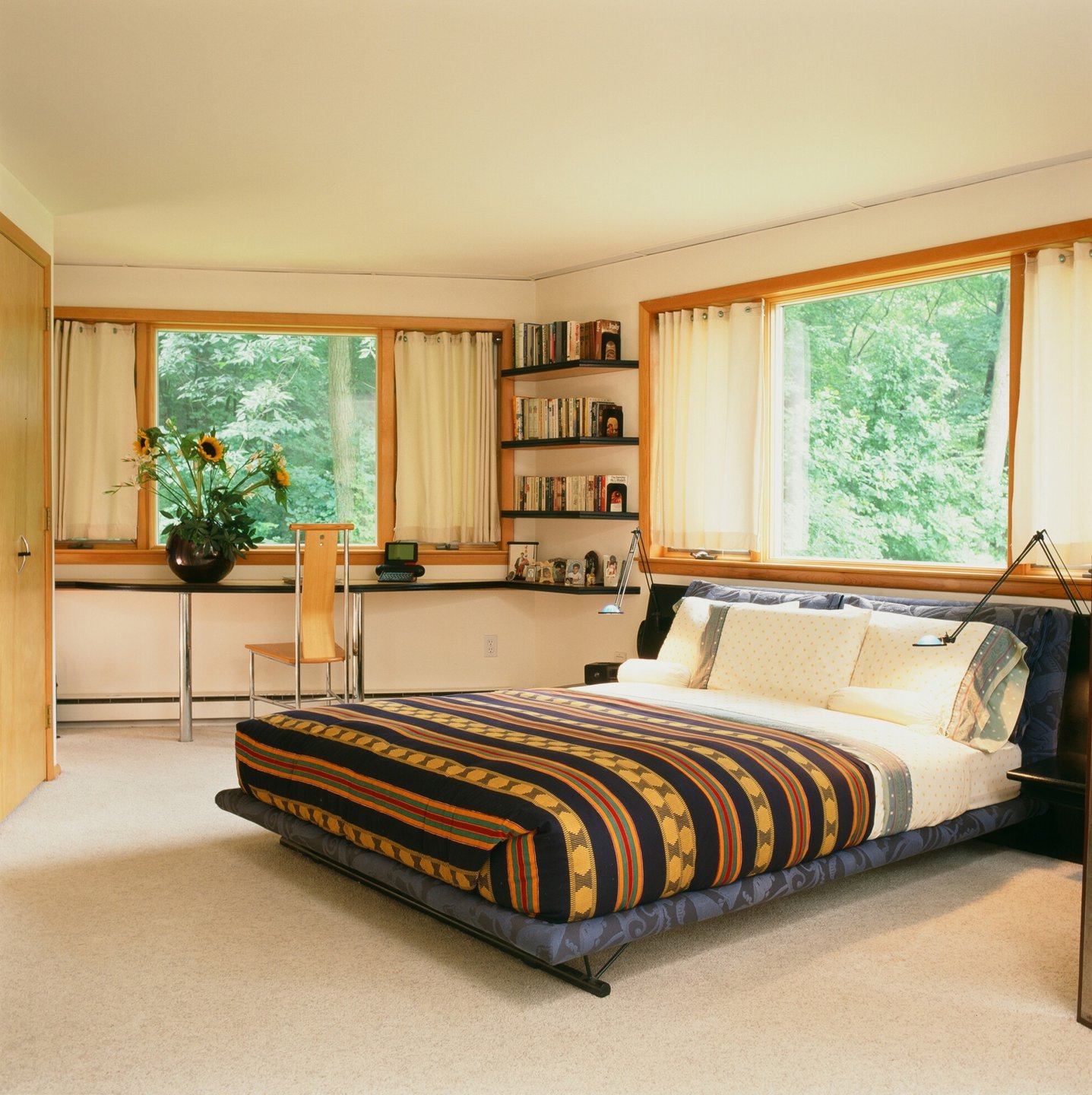 Usonia bedroom with windows showing surrounding forest