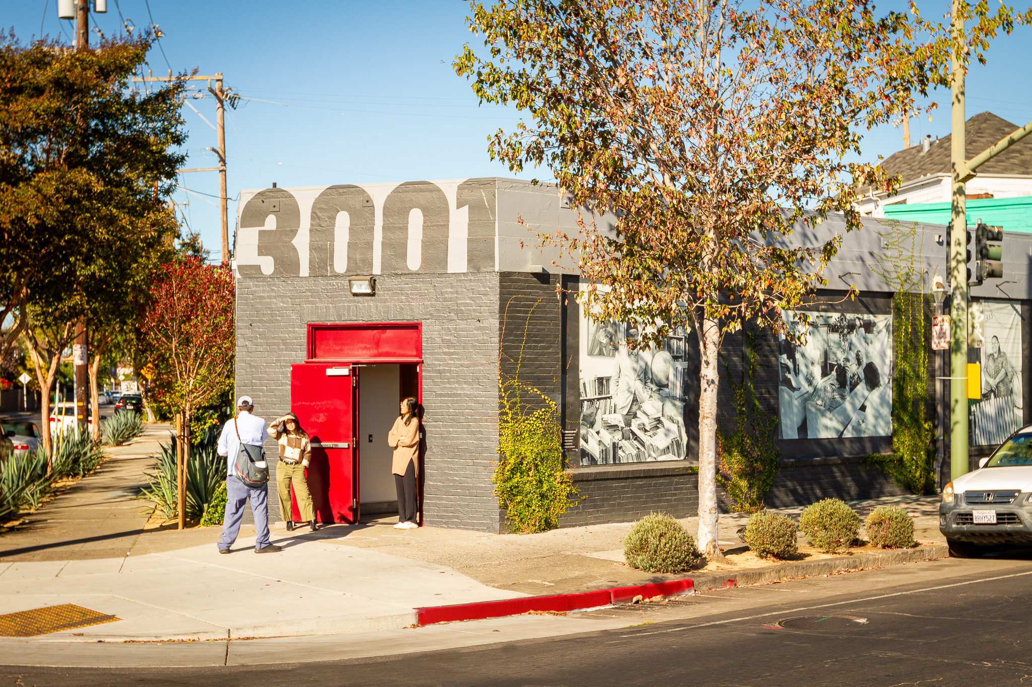 Gray building on street corner with red doors and large painted address above, "3001"