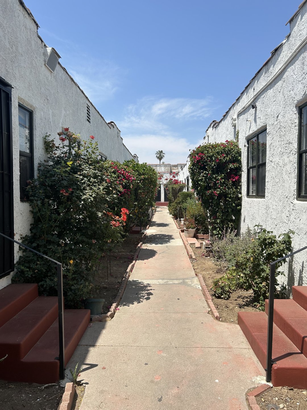 Brick and concrete pathway between either side of a white Bungalow Court