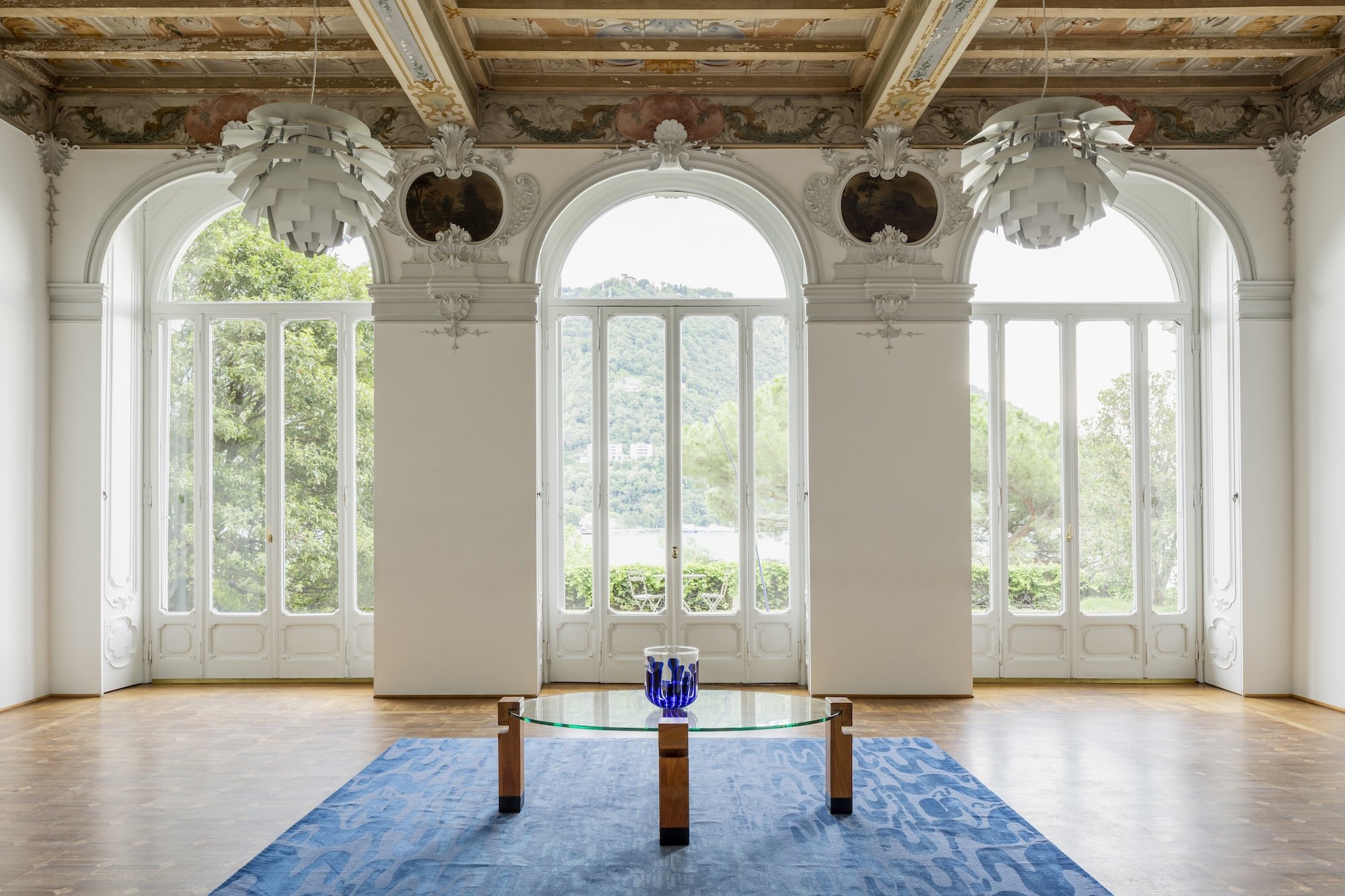 Inside the Villa del Grumello at the Lake Como Design Festival with three large windows and modern furniture on display