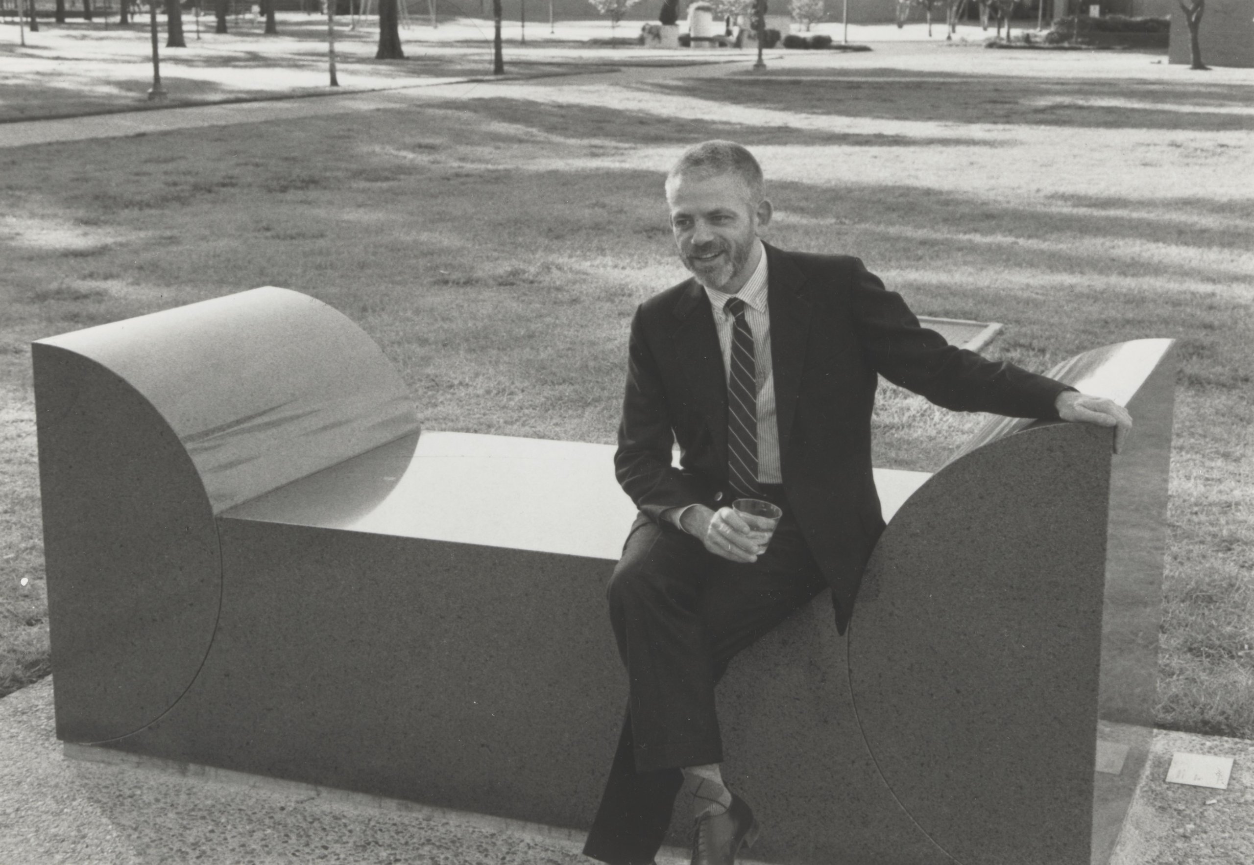 Black and white Scott Burton sitting on a chunky granite bench with semi-circle ends at the University of Houston