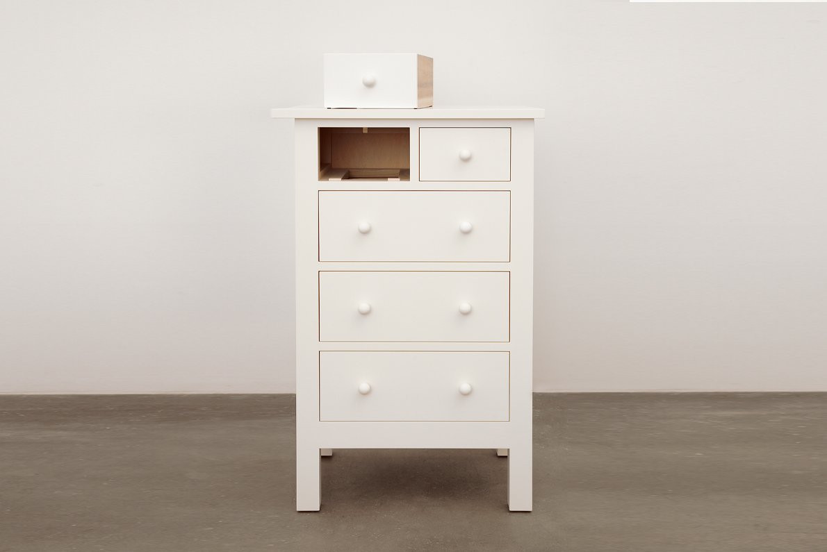 small white chest with five drawers and one is taken out and sitting on top of the chest
