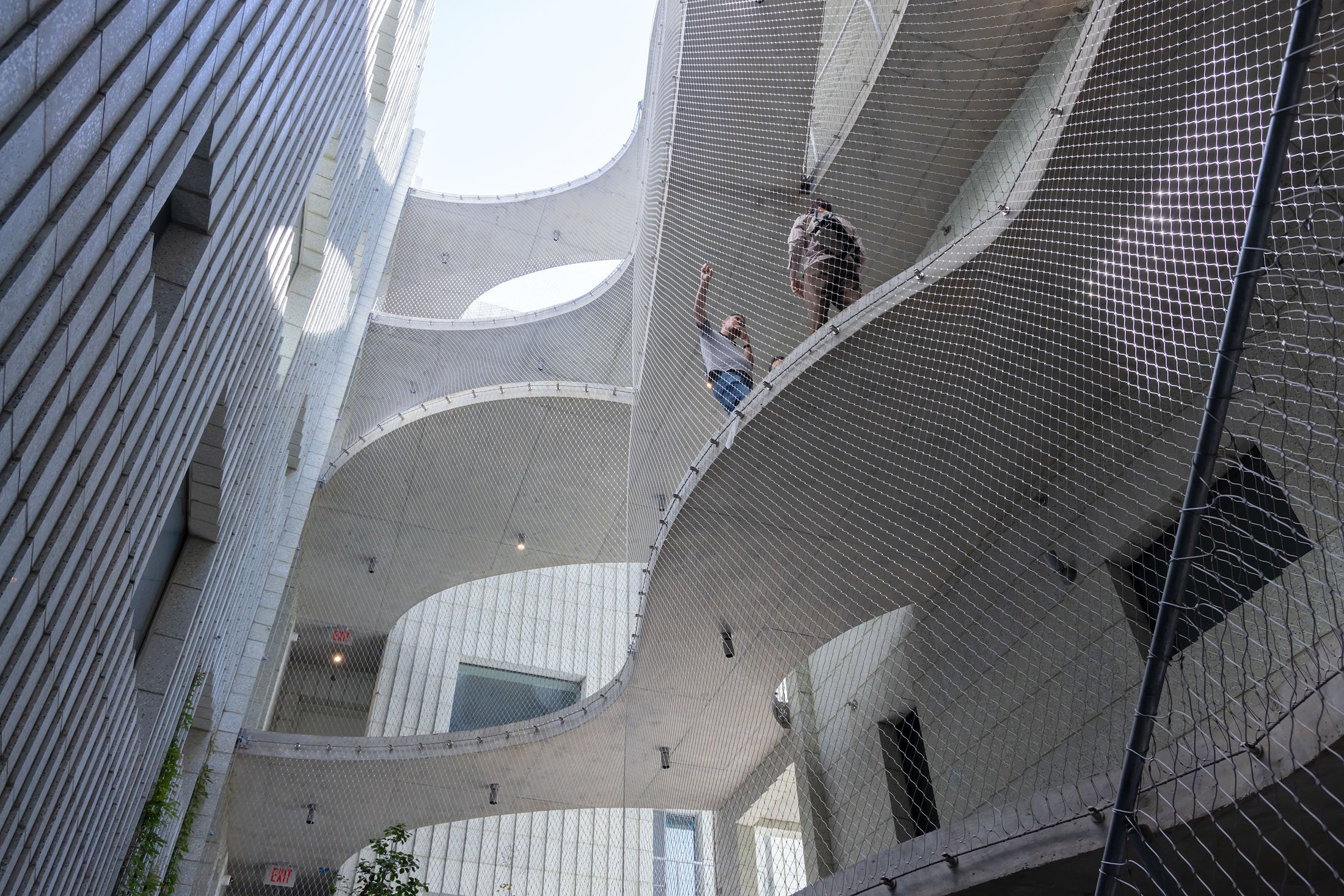 Floor-level view looking up at modern concrete building with sky bridges linking apartments to each other