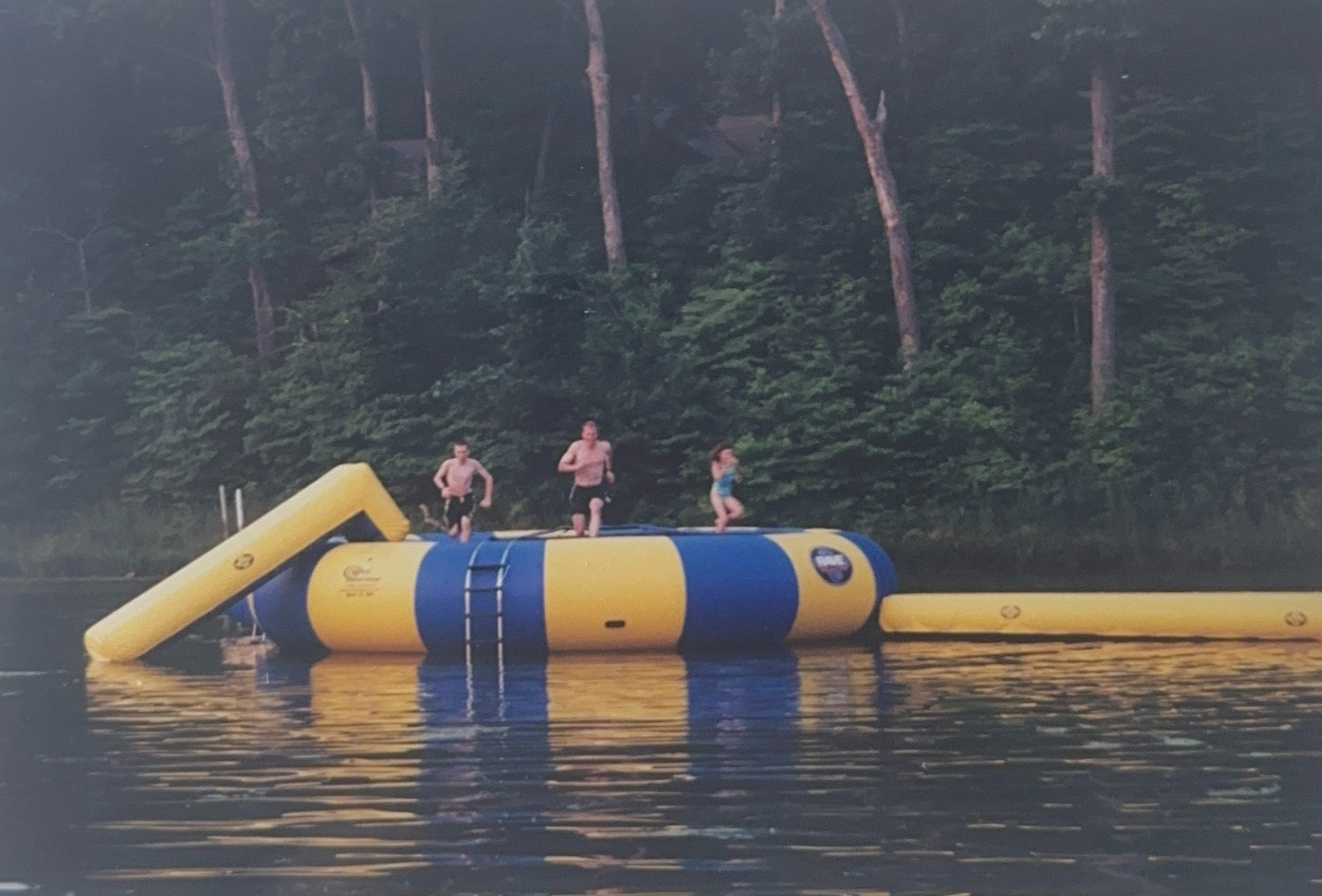 Three people and a blow up floating toy on a lake