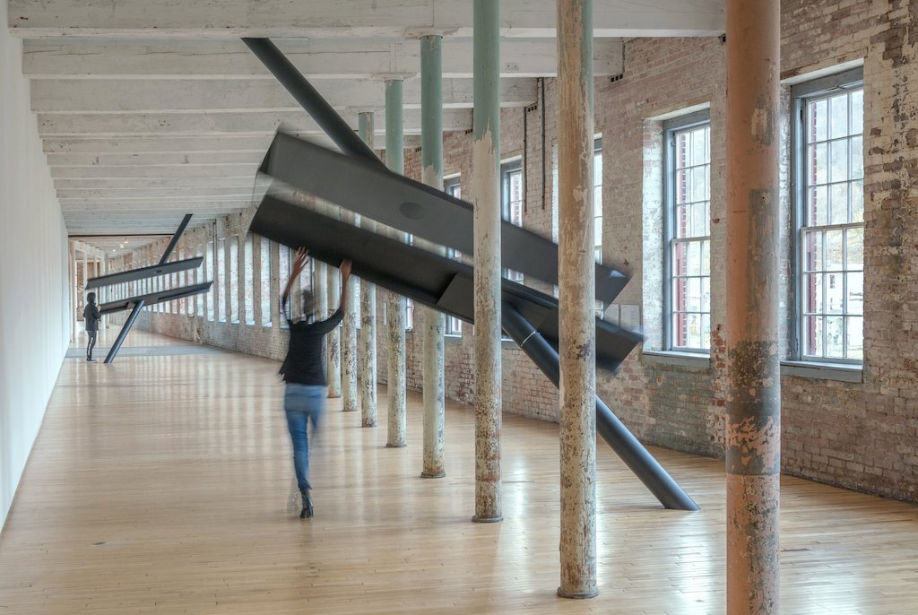 Installation view of a blurred person interacting with Sarah Oppenheimer’s artwork, “S-334473” (2019)