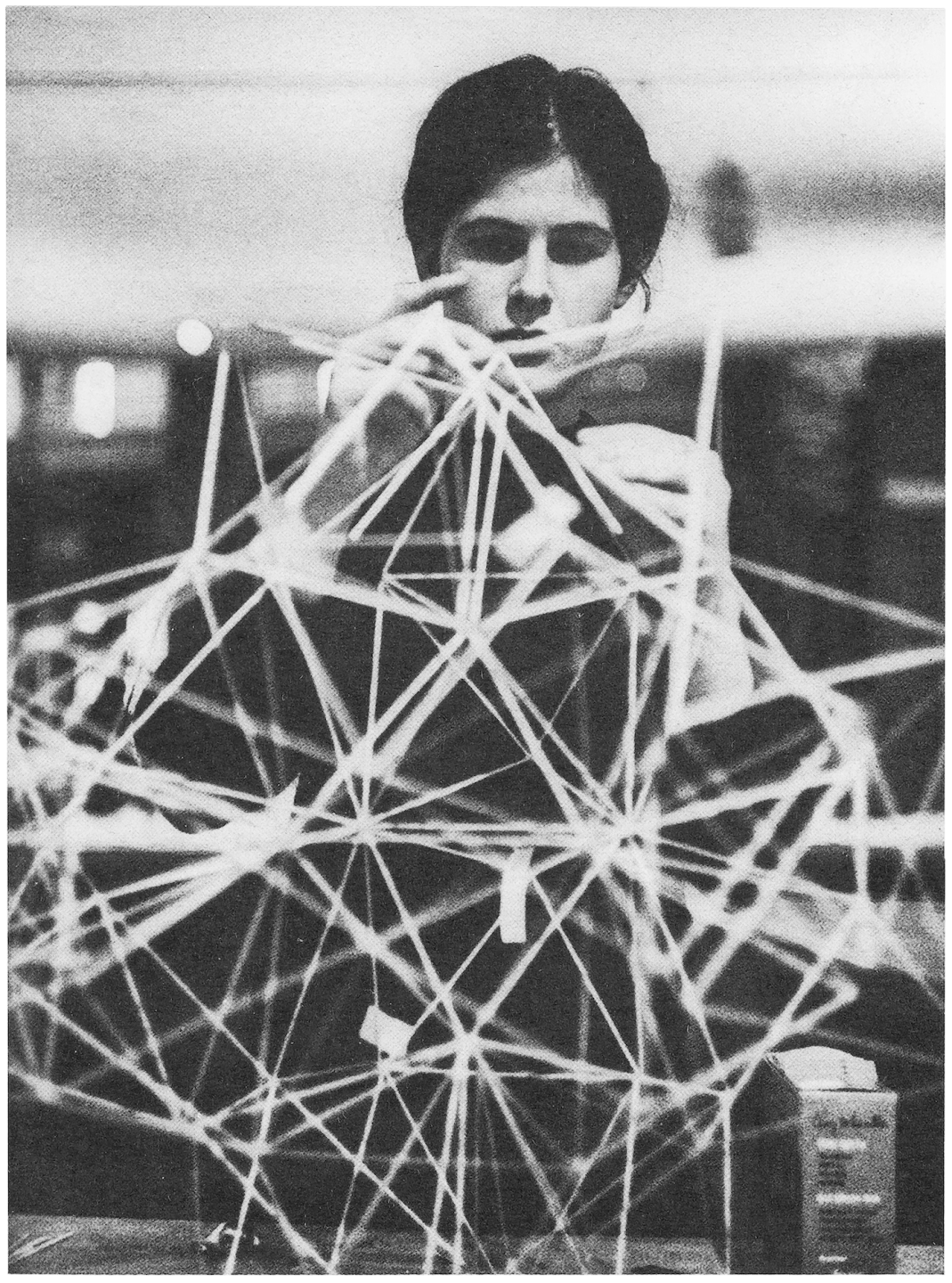 A girl building an architectural model using small sticks