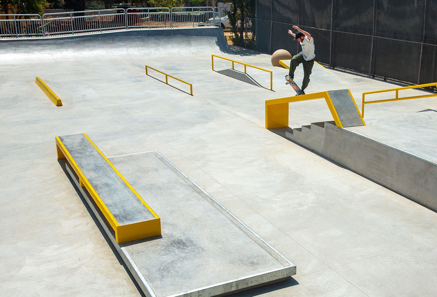 A California skate park with yellow trim and a skate borderer doing a trick